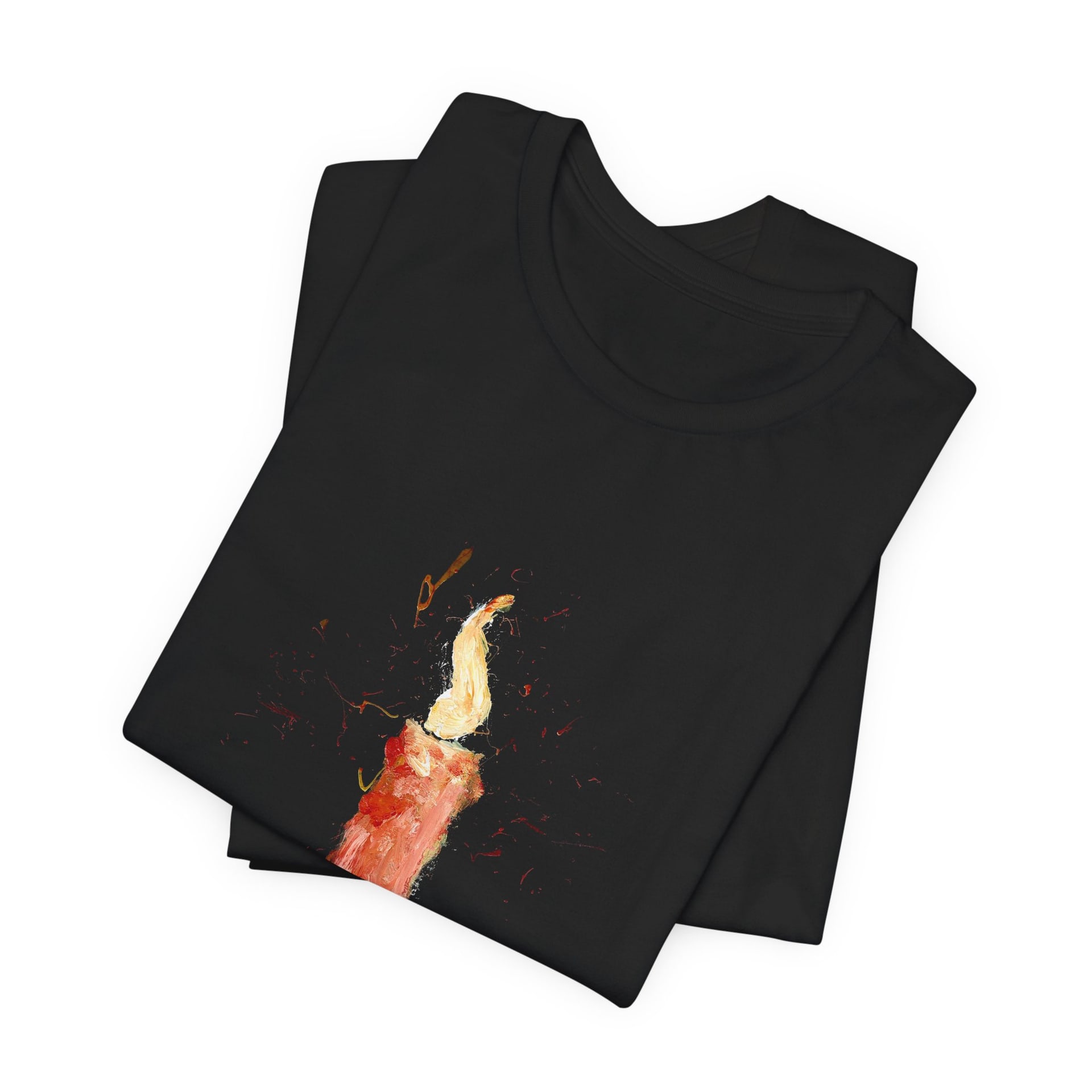 The black t-shirt folded into a neat square, the painted candle and its flame running diagonally across the top fold.
