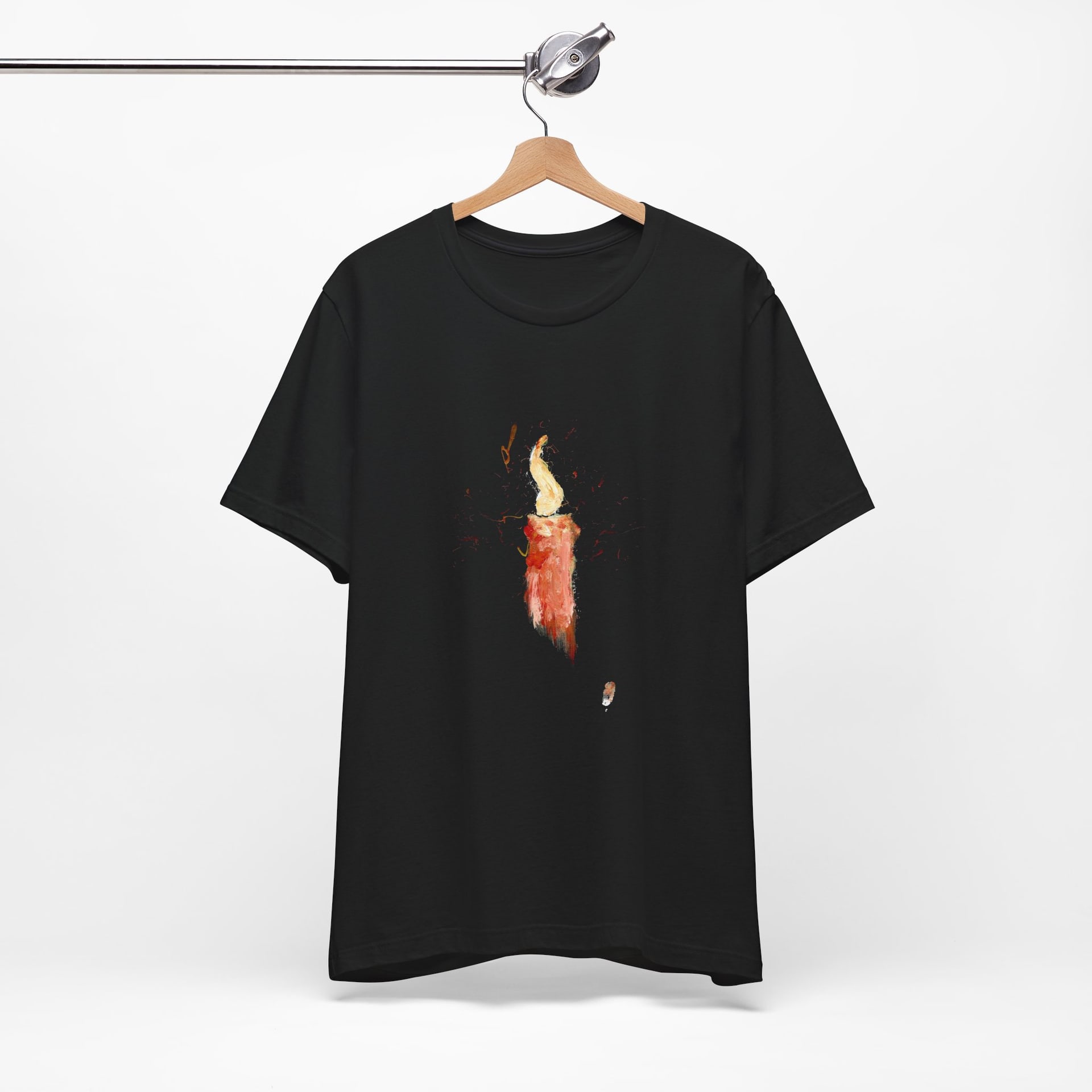 The black t-shirt on a wooden hanger suspended from a metal rail, the painted candle centred on the chest.